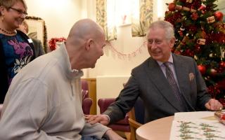 Hi Majesty spends time with a patient on a previous visit to Sue Ryder Leckhamton Court Hospice during his patronage as Prince of Wales