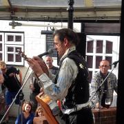 Ed Tudor Pole, telling an anecdote whilst changing a string, at Stroud Fringe Festival