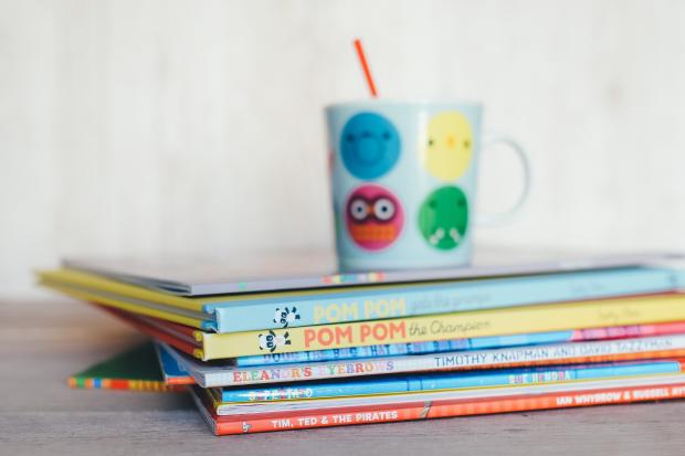 Stroud News and Journal: Children's books in a pile with a colourful mug on top. Credit: Canva
