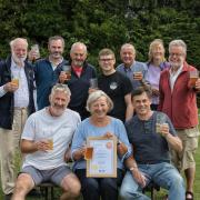 Ali Brady (middle) with Rob and Tony Hill (Chair of Stroud CAMRA) while Stroud CAMRA members gather round to toast their achievement -  photo by Rachel Andrews